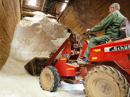 Loses Rohmaterial im Rohstofflager Suberg. Arbeiter mit Maschine im Vordergrund.